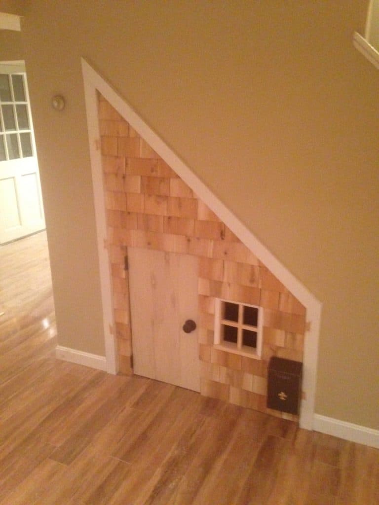 Small shingled playhouse door built into the space under a basement stair
