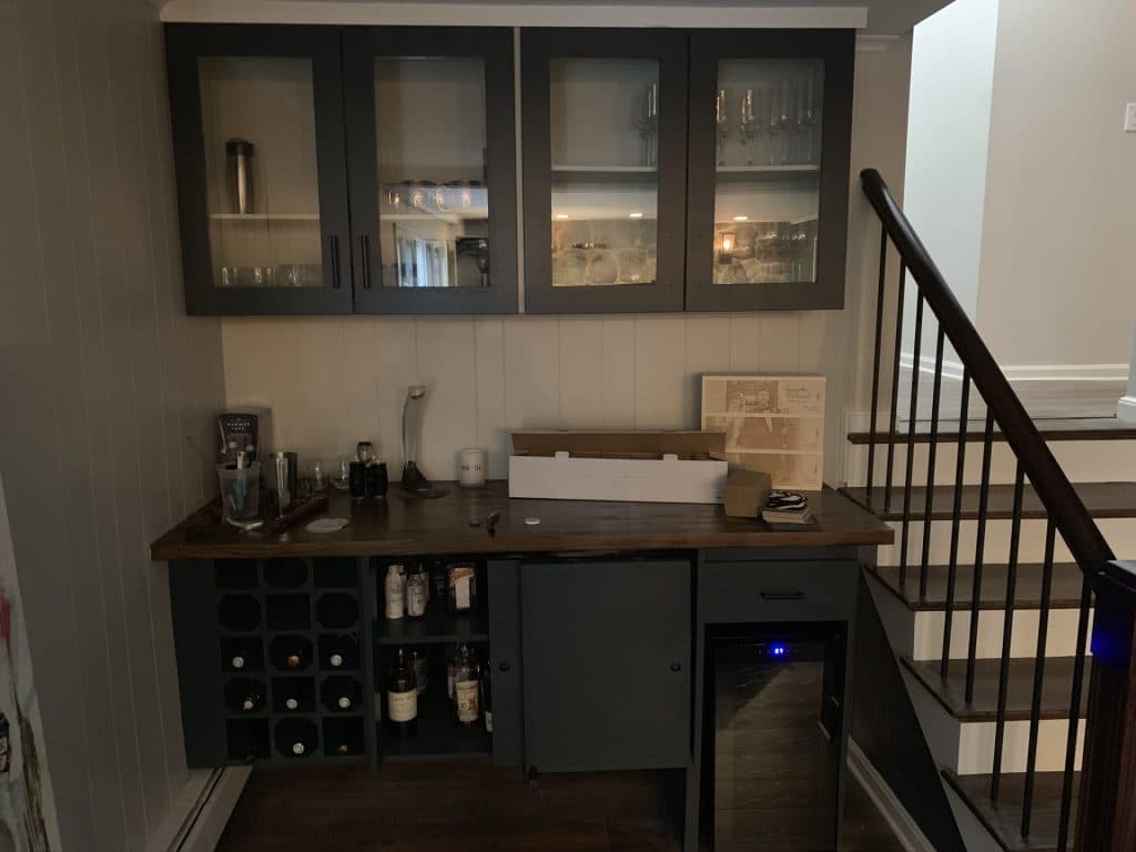 Basement wet bar with glass-front cabinets and wine storage beside the stairs