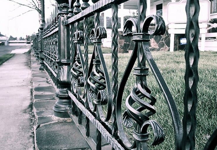 Close-up of a wrought iron fence with scroll and twist details